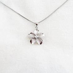 Introducing our exquisite Silver Plumeria Flower Necklace, a stunning piece that encapsulates the beauty of nature. This captivating necklace features a meticulously crafted Plumeria flower pendant adorned with sparkling Cubic Zirconia, adding a touch of brilliance to your look. The silver finish exudes elegance and sophistication, making it a perfect accessory for any occasion. The necklace comes with an 18-inch Rhodium Plated Box Chain, ensuring a comfortable and secure fit. Rhodium plating pr Nature-inspired Jewelry With Flower Charm, Nature-inspired Silver Jewelry For Gifts, Nickel-free Flower Pendant Jewelry For Her, White Gold Flower Charm Necklace, Elegant Silver Flower Necklace With Round Pendant, Elegant Nickel-free Flower Shaped Necklace, Nickel-free Flower Pendant Jewelry As Gift For Her, Delicate White Gold Flower Pendant Necklace, Silver Flower Shaped Jewelry For Mother's Day