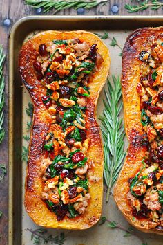 two delicacy squash halves on a baking sheet with herbs and seasoning sprigs