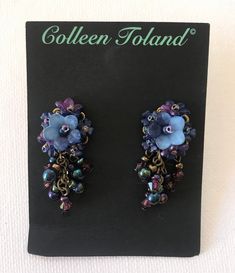 Lovely Navy Blue Flower Earring. A single larger flower on top of the ear, surrounded by dainty small flowers in a purple hue and finished with several drop beads in Aurora Borealis colors (rainbow blue). The flowers are hand colored by me and they are hand beaded together with glass seed beads. A pretty earring that's very wearable for day time. Matching jewelry listed below. This is a quality piece of jewelry that will last a life time. Created by designer Colleen Toland who has been creating Elegant Lavender Beaded Earrings, Blue Handmade Flower Drop Earrings, Elegant Adjustable Flower Shaped Beaded Earrings, Elegant Blue Flower Charm Earrings, Elegant Flower-shaped Earrings With Dangling Beads, Purple Flower Jewelry With Handmade Details, Purple Flower-shaped Jewelry With Handmade Flowers, Handmade Purple Flower Earrings, Purple Flower Jewelry With Handmade Flowers