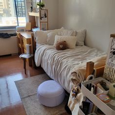 a bed sitting in a bedroom next to a window with lots of clutter on it