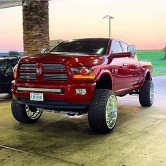 a red ram truck parked in front of a palm tree