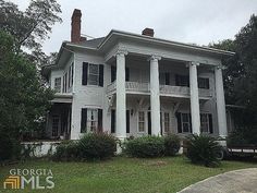 a large white house sitting on top of a lush green field