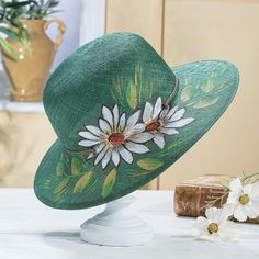 In 1989, Luigi & Marisa of Montapone, Italy, collaborated to begin a milliner's workshop. Today, almost 30 years later, their timeless hats are sold to collectors worldwide. This green Italian straw sun hat features hand-painted white flowers and sun-kissed leaves naturally complimenting any outfit. 22'' inner circumference.