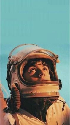 a man in an astronaut's helmet looks up at the sky with his eyes wide open