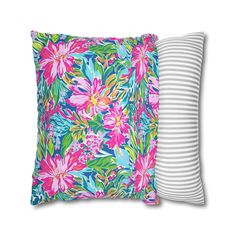 two pillows with colorful flowers on them, one in white and the other in pink