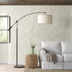 a living room with a white couch and floor lamp next to a basket on the floor