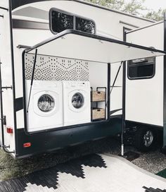 an rv is parked in the grass with its door open and two washers attached to it