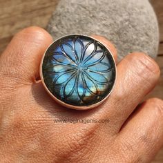 * Product Information Adorn your hand with our exquisite hand-carved floral design labradorite ring. Crafted in sterling silver, this statement piece features a round shape with mesmerizing orange and blue hues. Elevate your style with this unique and elegant accessory. ✦ M E T A L : Sterling Silver 925 ✦ S T O N E : Labradorite ✦ W E I G H T : 20 Gms ✦ S I Z E : 32 X 32 MM ✦ B I R T H S T O N E : February 💎  Labradorite is renowned for its metaphysical properties, offering protection against negative energies while promoting clarity and intuition. Its iridescent sheen stimulates imagination and creativity, fostering a deeper connection to one's inner wisdom and spiritual growth. Labradorite is also believed to enhance psychic abilities and promote balance and harmony in mind, body, and s Spiritual Carved Round Ring, Spiritual Labradorite Round Ring, Unique Carved Round Rings, Spiritual Labradorite Rings, Handmade Nature-inspired Round Moonstone Ring, Handmade Spiritual Flower Ring, Nature-inspired Round Labradorite Jewelry, Bohemian Carved Round Ring, Bohemian Carved Ring