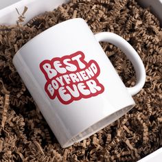 a white coffee mug with the words best boyfriend ever printed on it in a pile of wood shavings