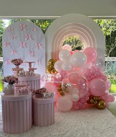 pink and gold balloons are on display in front of a birthday party backdrop with an arch