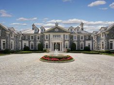 a large house with a fountain in the middle of it's front lawn area