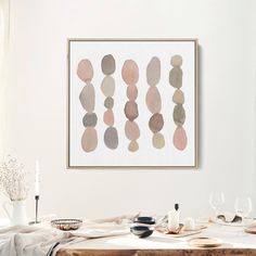 a dining room table with plates and glasses on it, next to a framed art piece