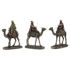 three figurines of men riding on camels