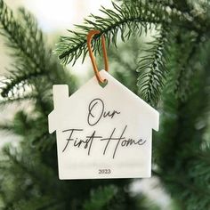 a house ornament hanging from a christmas tree with the words our first home written on it