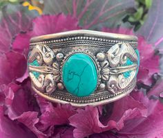 Vajra or Dorje Cuff bracelet. This is a beautiful Tibetan inspire Tribal Cuff with Vajra and Turquoise in the middle. Turquoise stone in the middle is carefully nested in the metal strip and also has inlaid turquoise around the cuff with intricate hand work. Made with a beautiful old time vintage appeal to it. Casual and cool piece to match with any outfit. Completely adjustable to any adult wrist size and is very comfortable to wear. Perfect for Male or Female. Size: 2.75" X 1.60" Southwestern Style Turquoise Bangle As A Gift, Handmade Turquoise Spiritual Bangle, Handmade Spiritual Turquoise Bangle, Unique Turquoise Nickel-free Cuff Bracelet, Bohemian Turquoise Nickel-free Cuff Bracelet, Unique Nickel-free Turquoise Cuff Bracelet, Adjustable Turquoise Bangle For Festivals, Spiritual Turquoise Bangle As Gift, Turquoise Bangle Cuff Bracelet Gift