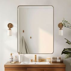 a bathroom vanity with a large mirror above it and gold faucets on the wall