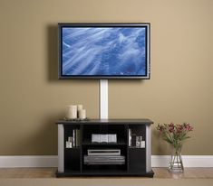 a flat screen tv mounted to the side of a wall next to a vase with flowers