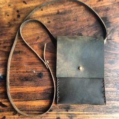 a small leather bag sitting on top of a wooden table next to a brown string