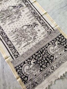 an intricately designed black and white scarf on a marble countertop, with the image of lord ganesh