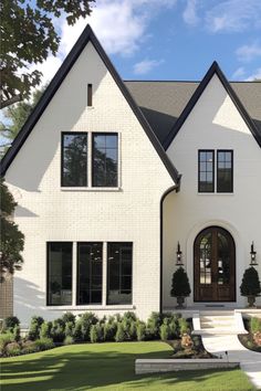 a large white house with black trim on the front door and two story entryway