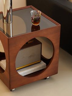 a wooden table with a radio on it and a glass top sitting on the floor