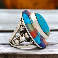 This stunning sterling silver ring, crafted by Robert Drozd featuring a unique multi-stone inlay design, showcasing a harmonious blend of vibrant turquoise, coral, and black onyx stones. Each stone is carefully selected and arranged to evoke the rugged elegance of the canyon landscape, with the turquoise evoking the clear desert skies, the coral recalling the warm hues of sunset, and the black onyx representing the mystery of the canyon's depths. With its expert craftsmanship and Southwestern ch Adjustable Multicolor Multi-stone Turquoise Ring, Unique Multicolor Oval Gemstones, Multicolor Oval Fusion Rings, Southwestern Multicolor Gemstone Turquoise Ring, Southwestern Multicolor Turquoise Gemstone Ring, Multicolor Multi-stone Turquoise Ring, Bohemian Multi-stone Turquoise Ring, Artisan Multicolor Multi-stone Rings, Multicolor Turquoise Gemstone Ring In Sterling Silver