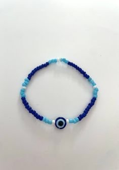 a super cute bracelet with an evil eye in the middle followed by a cute pattern of blues and white! stretchy and durable. Evil Eye Bead Bracelet, Blue Spiritual Stretch Bracelet For Beach, Spiritual Blue Stretch Bracelet For Beach, Casual Adjustable Beaded Bracelet With Evil Eye, Casual Blue Friendship Bracelets With Evil Eye, Blue Spiritual Bracelets With Letter Beads, Spiritual Blue Bracelets With Letter Beads, Casual Multicolor Beaded Evil Eye Bracelet, Trendy Hand-strung Blue Beads