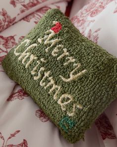 a close up of a green pillow on a bed with red and white comforter