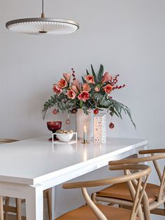 a white table with flowers and candles on it in front of a light fixture hanging from the ceiling