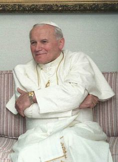 a man sitting on top of a couch in front of a framed photo with his arms crossed