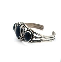 Vintage Sterling Silver Black Onyx Cuff Bracelet - The cuff bracelet features three pieces of striking black onyx and is adorned with expertly-crafted silverwork. The triple wire shank provides both comfort and durability. This well-made Southwest piece is substantial and built to withstand the test of time. Black Onyx Size: S/M 7" Cuff includes 1" Gap Inner circumference 7" total Stone (center): 1"L x .75"W Metal: Sterling Silver Weight: 33.5 Grams This listing is for (1) Cuff only Explore our curated selection of exceptional Vintage Bracelets here. Discover the entire 'Silver Raven' Vintage Collection for yourself. Classic Black Cuff Bracelet Bangle, Classic Black Cuff Bracelet In Bangle Style, Black Polished Cuff Bracelet For Formal Occasions, Formal Black Cuff Bracelet With Polished Finish, Formal Black Polished Cuff Bracelet, Adjustable Black Sterling Silver Cuff Bracelet, Adjustable Black Cuff Bracelet With Polished Finish, Raven Jewelry, Silver Work