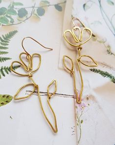 A  beautiful pair of hand shaped brass wire wild flower inspired earrings Based on a simple outline drawing I did of a wild flower, I used wire to replicate its lines and shapes.  These earrings are delicate, lightweight and so easy to wear They are made from gold brass wire, and are hung from gold plated french hooks They are minimalist and graceful The measure approximately 7cm from the top of the hook to the bottom of the stem Whimsical Gold Wire Wrapped Earrings, Nature-inspired Gold Wire Wrapped Earrings, Nature-inspired Gold Flower Earrings With Ear Wire, Gold Whimsical Flower-shaped Earrings, Gold Nature-inspired Flower Earrings, Handmade Gold Flower Earrings For Spring, Whimsical Gold Flower-shaped Earrings, Simple Shapes Design, Simple Outline Drawing