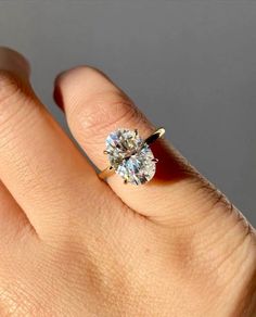 a person's hand with a diamond ring on top of their finger, showing the center stone