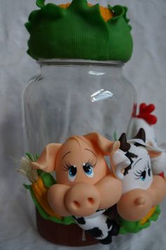 two small figurines in a glass jar with cow and corn on the cob