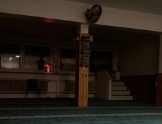 an empty room with a clock on the wall and stairs leading up to another room