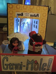 two dolls sitting on top of a cardboard box