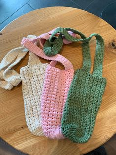 three crocheted bags sitting on top of a wooden table