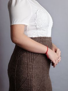 a woman wearing a skirt and white shirt is posing for the camera with her hands on her hips