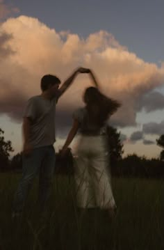 two people are standing in the grass with their arms around each other as they dance