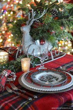 a christmas table setting with pine cones and greenery