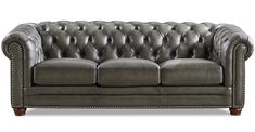 a gray leather couch with studding on the armrests and nail polishing