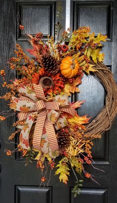 a wreath on the front door decorated with autumn leaves and pine cones