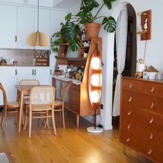 a living room filled with lots of furniture next to a wooden table and chair covered in potted plants