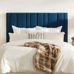 a bed with white linens and blue headboard