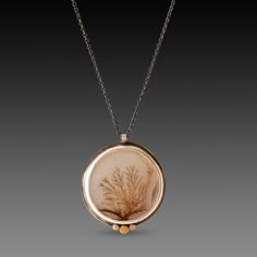 A very special dendritic agate evokes a mysterious and lovely scene in nature. The stone is wrapped in sterling silver and accented with a hammered 22k gold trio. Each of these incredible stones is one of a kind, and completely natural. Pendant measures approximately 7/8 inch in diameter, and is suspended from an oxidized sterling silver chain. Matte finish. This piece is in stock and ready to ship. Gold Moss Agate Pendant Jewelry, Gold Moss Agate Spiritual Necklace, Gold Moss Agate Round Jewelry, Unique Necklace With Natural Inclusions In Round Pendant, Nature-inspired Agate Round Pendant Necklaces, Nature-inspired Jewelry With Natural Inclusions In Round Pendant, Nature-inspired Agate Round Pendant Necklace, Nature-inspired Moss Agate Jewelry With Natural Inclusions, Agate Large Pendant Necklace In Nature-inspired Style