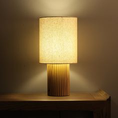 a lamp that is sitting on top of a wooden table in front of a wall