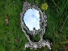 a mirror sitting in the grass on top of it's side with a sky reflection