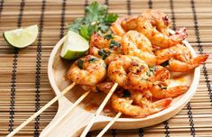 shrimp skewers with lime and cilantro on a wooden plate