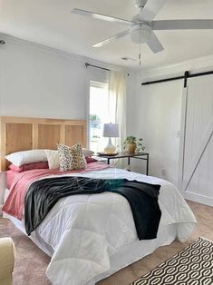 a bedroom with a bed, ceiling fan and rugs on the carpeted floor