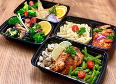 four trays filled with different types of food on top of a wooden table next to each other